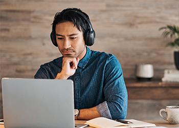 Man looking at laptop wearing headphones
